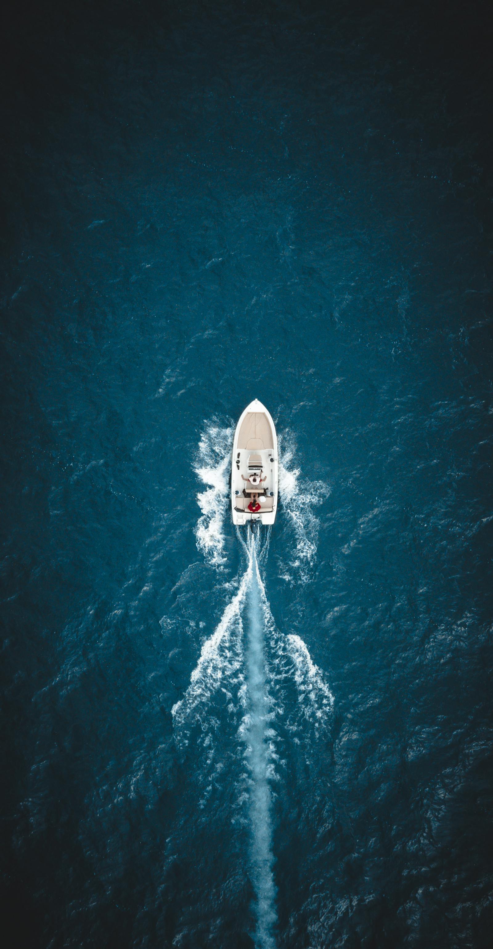 Boat sailing through turquoise Mediterranean waters near a rocky coast