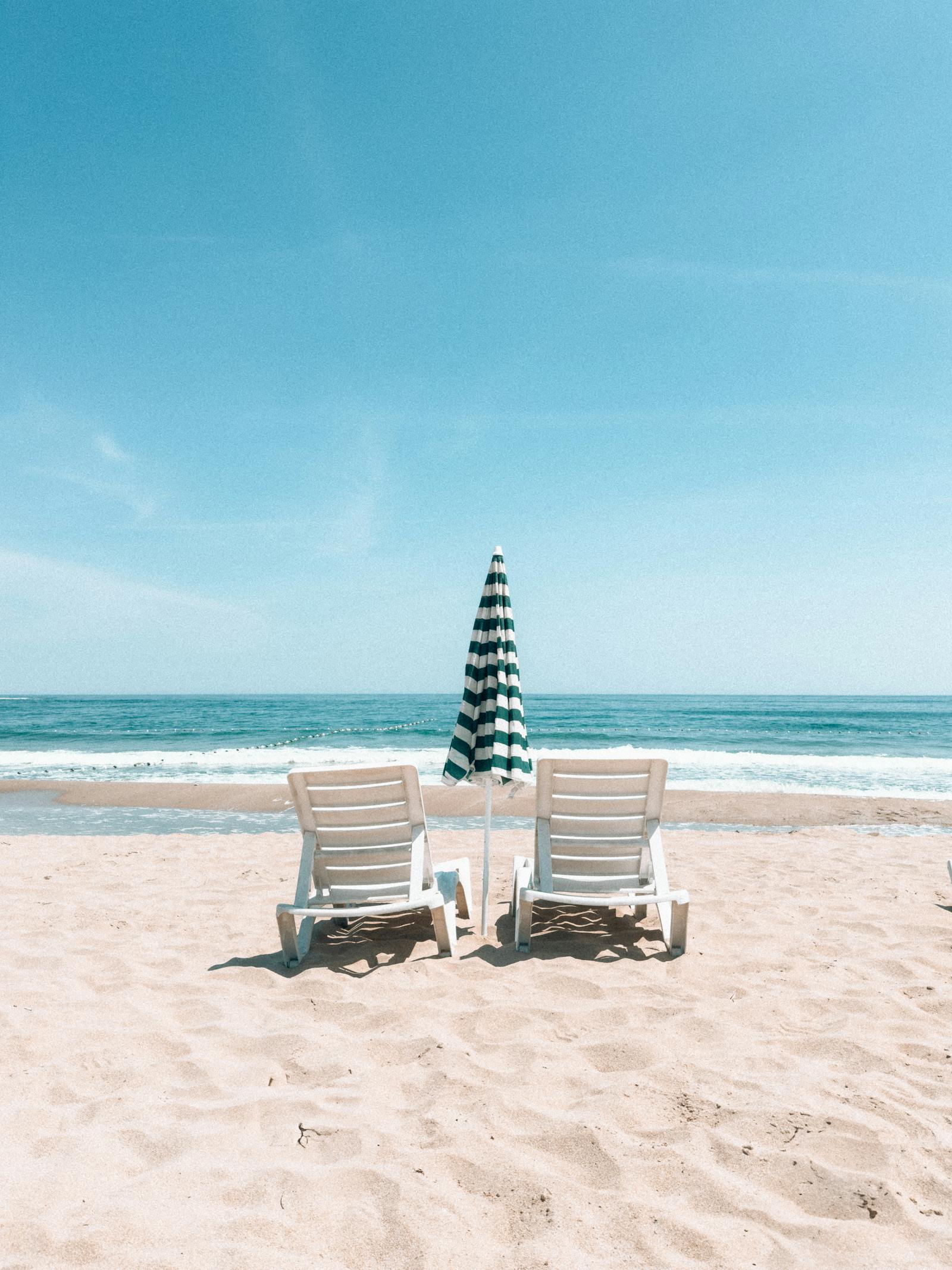 Beach umbrellas and sunbeds lined up on a sandy Mediterranean beach