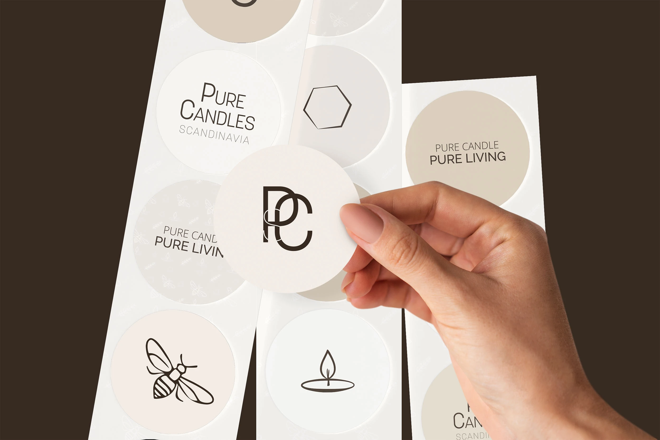 A hand holding a circular Pure Candles sticker, surrounded by various branded icons.