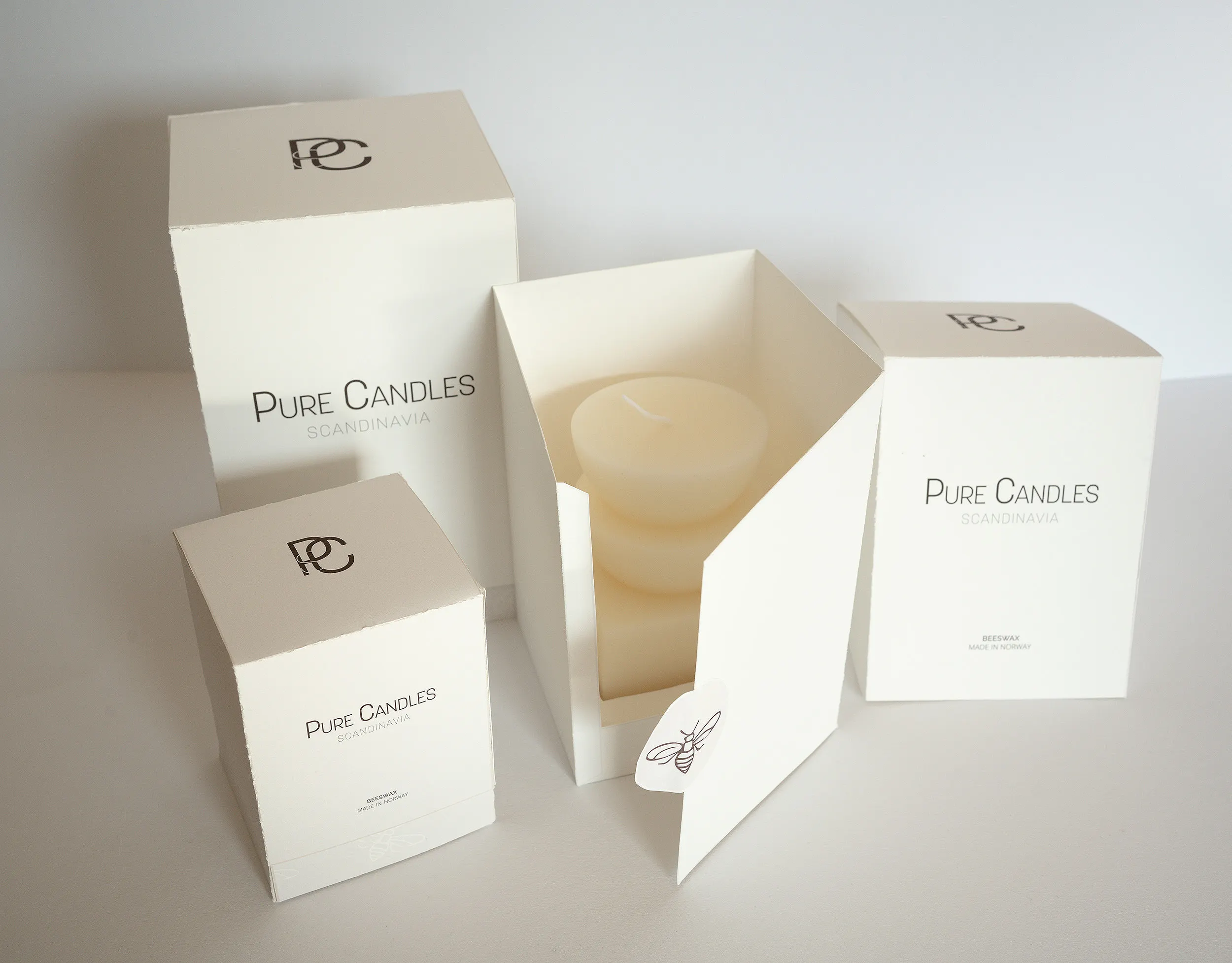 Pure Candles packaging shown from the top front, including an open box revealing the candle and a custom bee sticker.