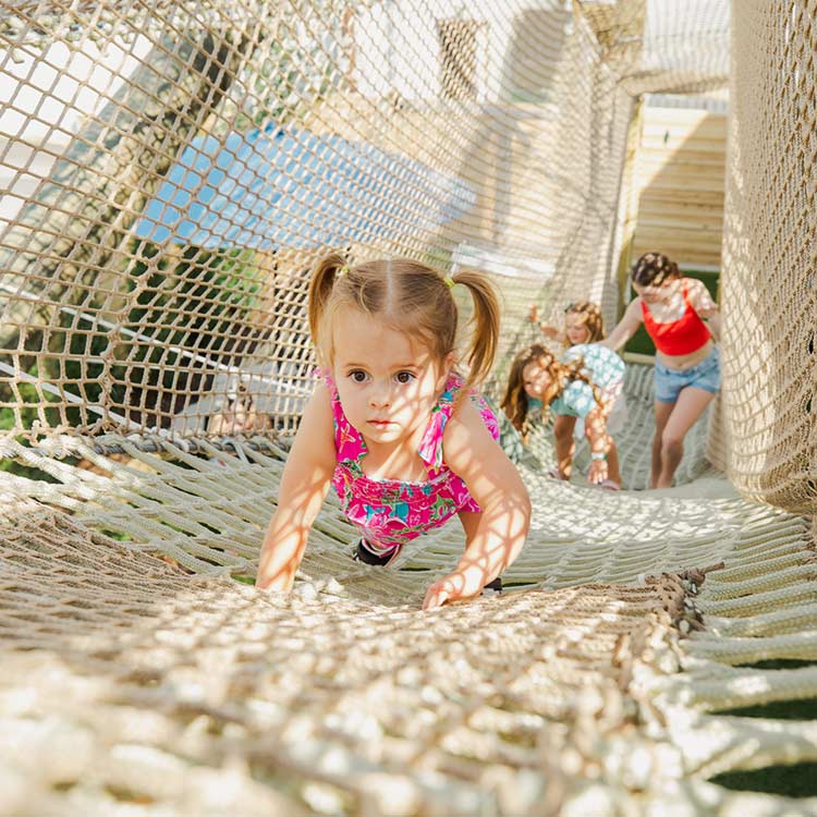 Young girl on the sky net playground at The Yard Ocean City NJ, climbing through a rope bridge for family fun