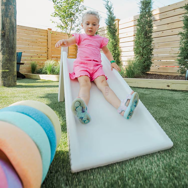 Toddler sliding down a play structure at The Yard Ocean City NJ outdoor play area for kids
