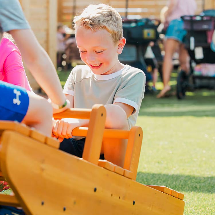 Smiling boy on a wooden seesaw at The Yard Ocean City NJ outdoor kids playground