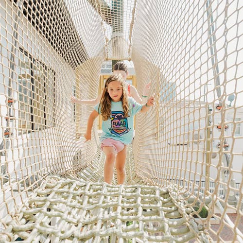 Girls playing on the elevated rope bridge at The Yard Ocean City NJ sky net playground