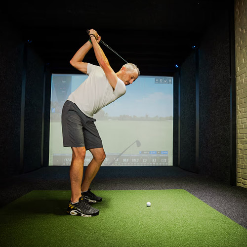 Adult man using the indoor sports simulator at The Yard Ocean City NJ for golf practice and fun