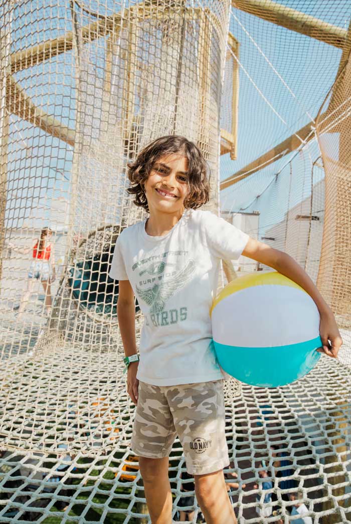 Smiling child holding a beach ball on the sky net playground at The Yard Ocean City, NJ