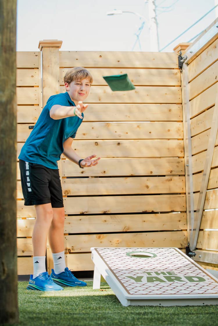 Boy tossing a beanbag during a cornhole game at The Yard in Ocean City, NJ