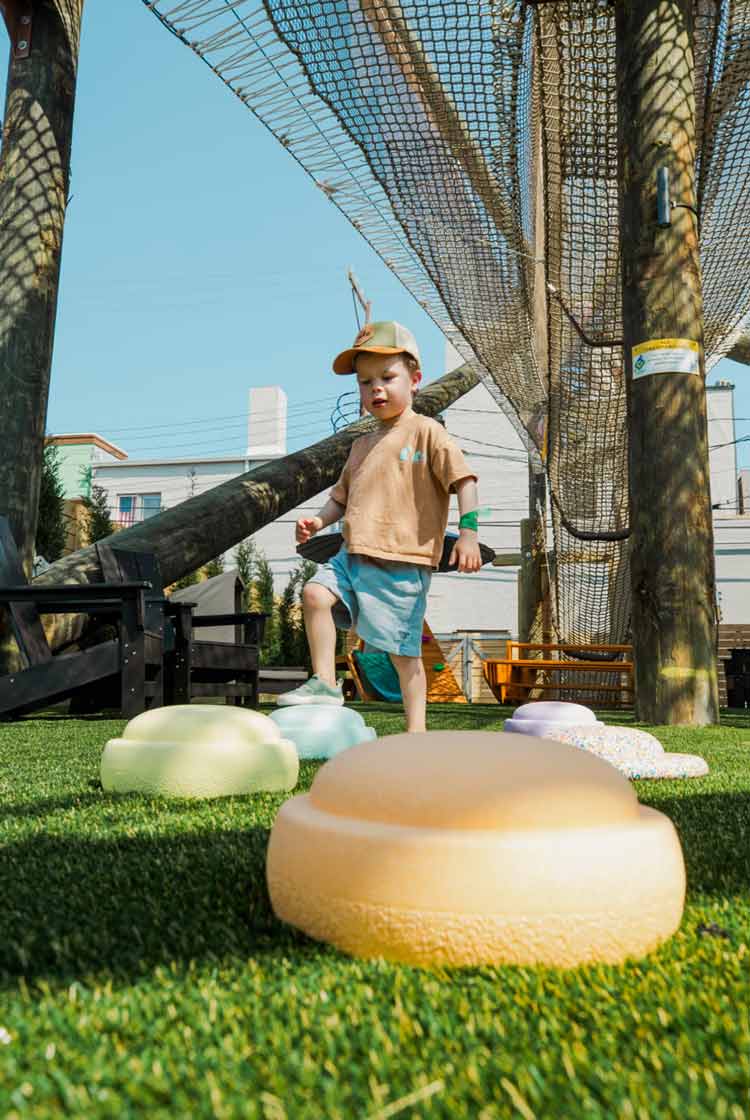 Young child playing on colorful soft stepping stones under netting at The Yard Ocean City, NJ