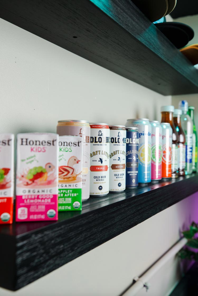 Assortment of canned drinks and juice boxes on black shelf at The Yard Ocean City, NJ snack bar