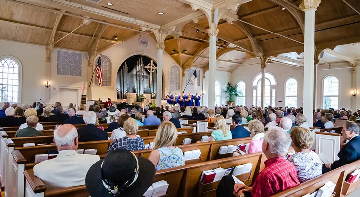 Churchgoers seated on wooden pews inside the Royal Poinciana Chapel
