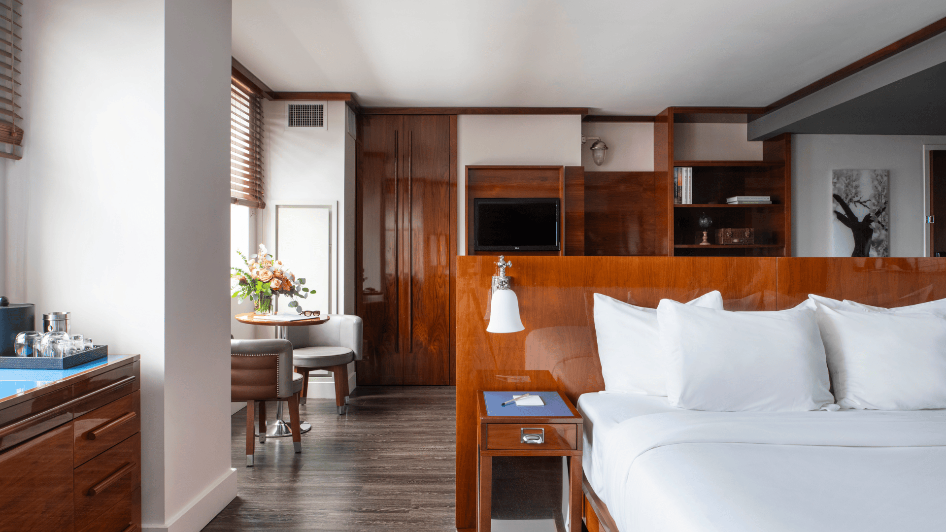 room at Hotel Hugo SoHo with floor-to-ceiling window overlooking the Hudson River and downtown Manhattan at sunset.