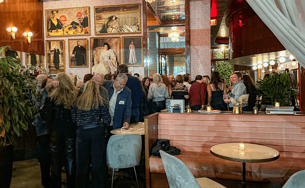 Indoor restaurant/bar with many people standing and sitting
