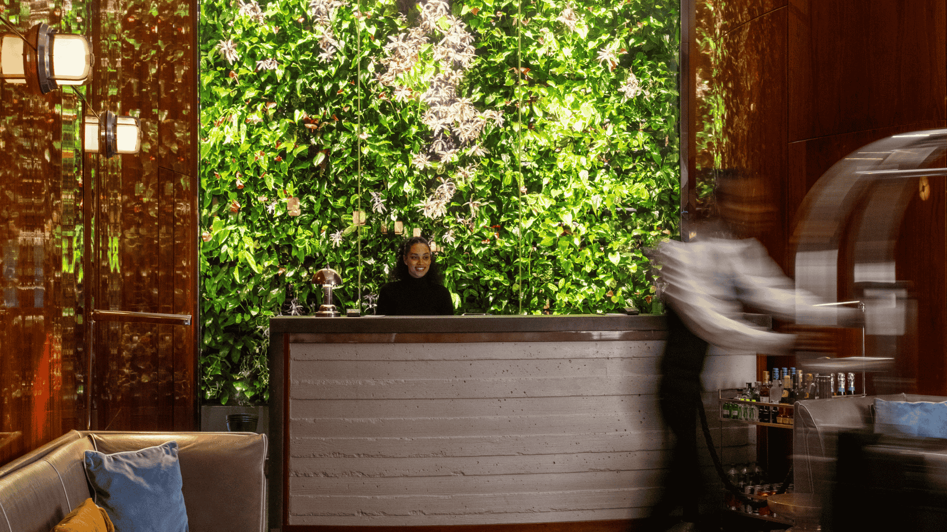 Hotel reception desk with green plant wall and staff member behind counter