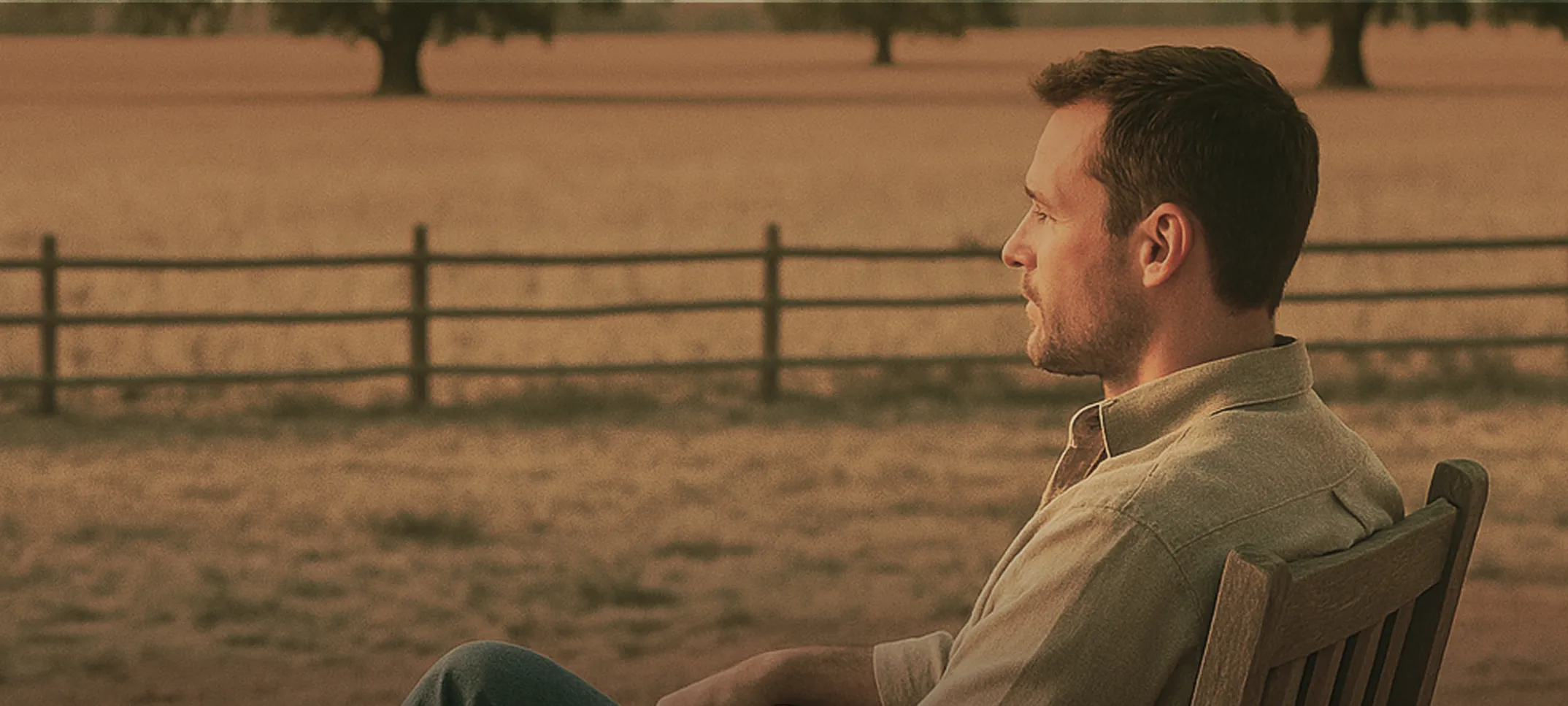 Man sat in a field at sunset