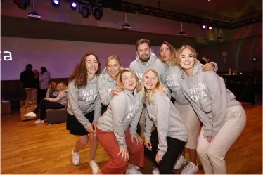 Eine Gruppe von b.telligent Mitarbeiterinnen in Hoodies lächelt in die Kamera