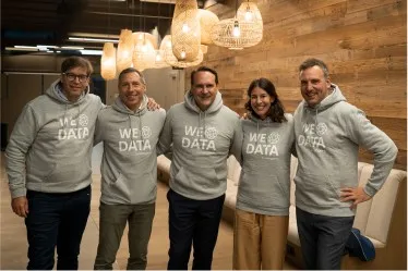 Fünf Personen in b.telligent Hoodies lächeln in die Kamera