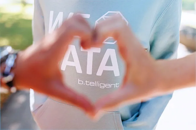 Zwei Hände formen ein Herz, im Hintergrund ein b.telligent Pullover mit dem Aufdruck Data