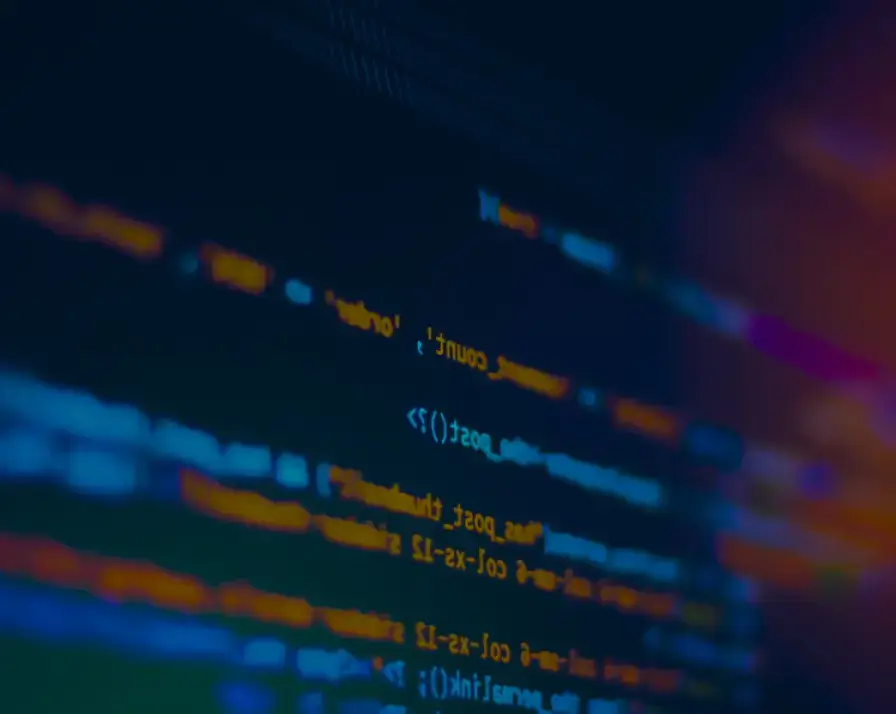 A close-up shot of a computer screen displaying lines of colorful code related to identity theft protection in various programming languages. The lines of text include keywords and symbols highlighted in blue, orange, red, and green on a dark background, giving a neon-like effect.