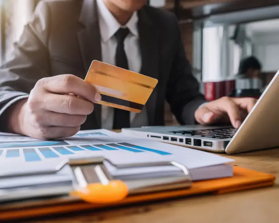 Businessman on computer looking at credit card