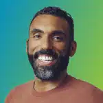 A person with short curly hair and a beard smiling widely while looking forward. The background is a gradient of blue to green, symbolizing tranquility and trust, just like reliable identity theft protection.