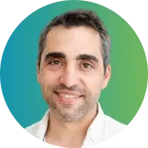 A smiling man with short dark gray hair and a light beard. He is wearing a white shirt and is set against a circular background that transitions from blue on the left to green on the right, highlighting his professional bearing and expertise in employee benefits.