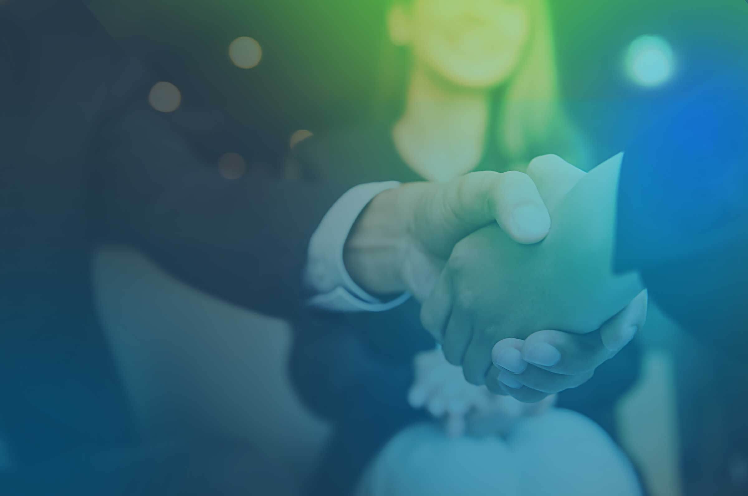 Two individuals shaking hands in a business setting, with a blurred background and a gradient overlay in green and blue tones.