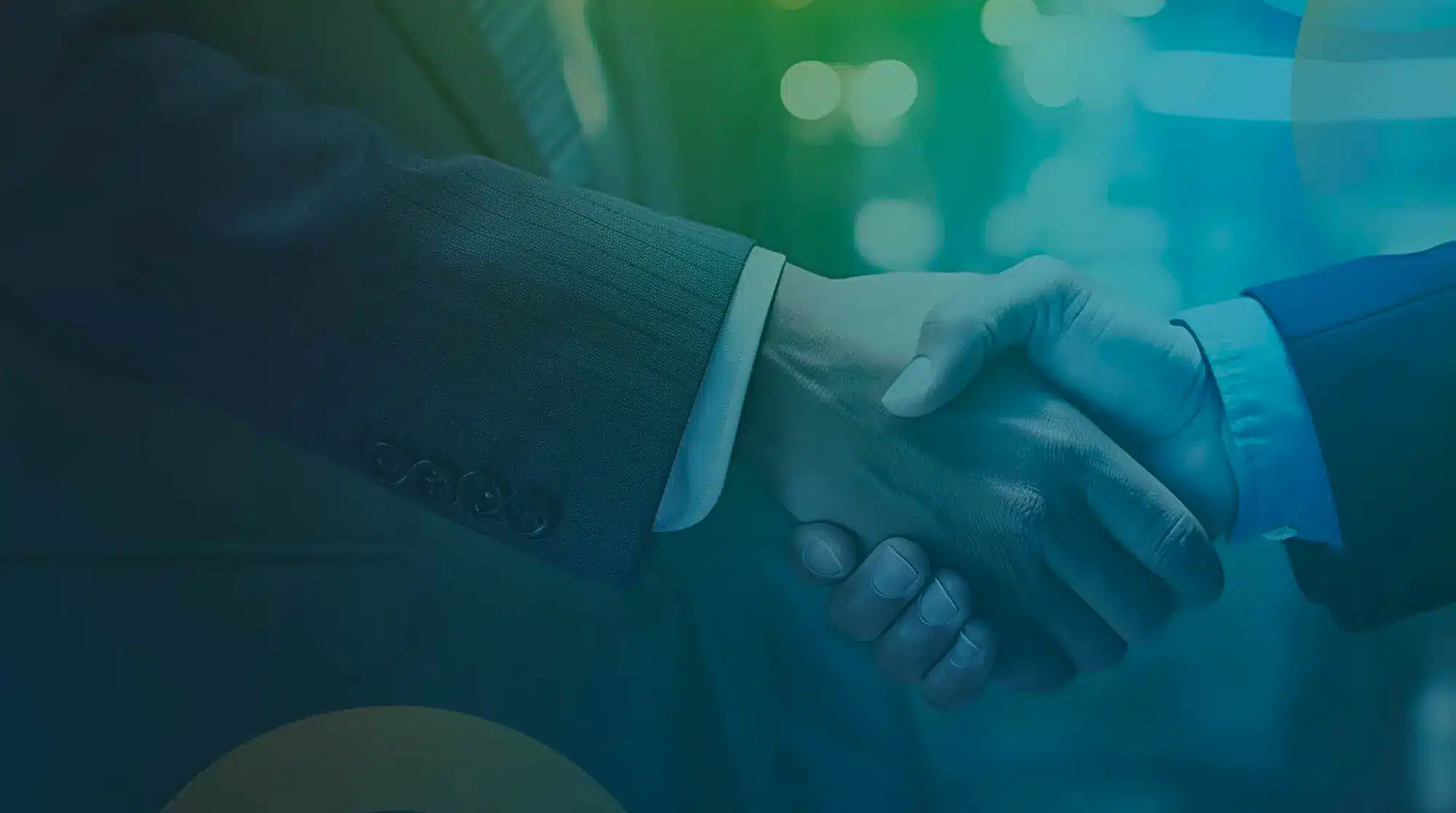 Two people in business suits shaking hands, symbolizing a business agreement or partnership. The background is blurred with a blue and green gradient, giving a professional and modern feel to the image, indicative of discussions about employee benefits.