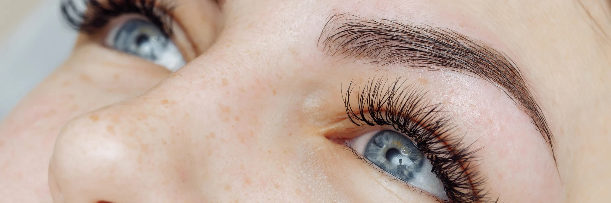 Primo piano di occhi femminili con extension ciglia voluminose e naturali, luce calda