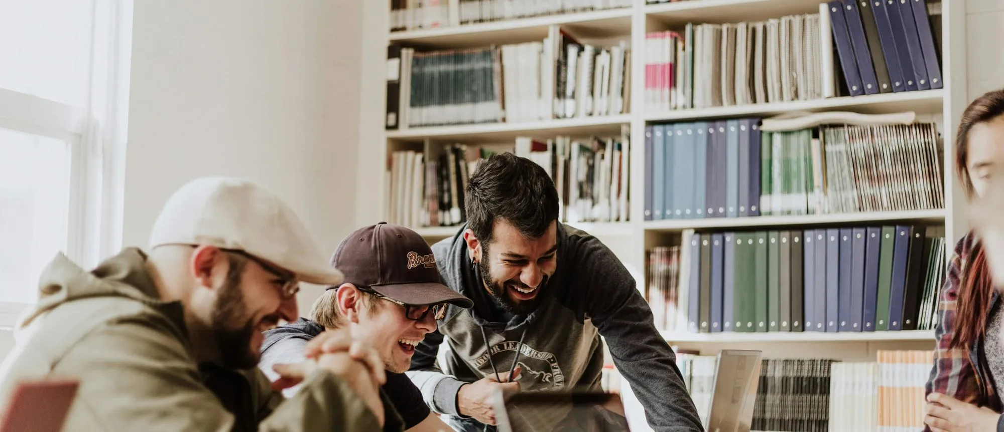 A diverse group of individuals collaborating on a laptop in a quiet library setting.
