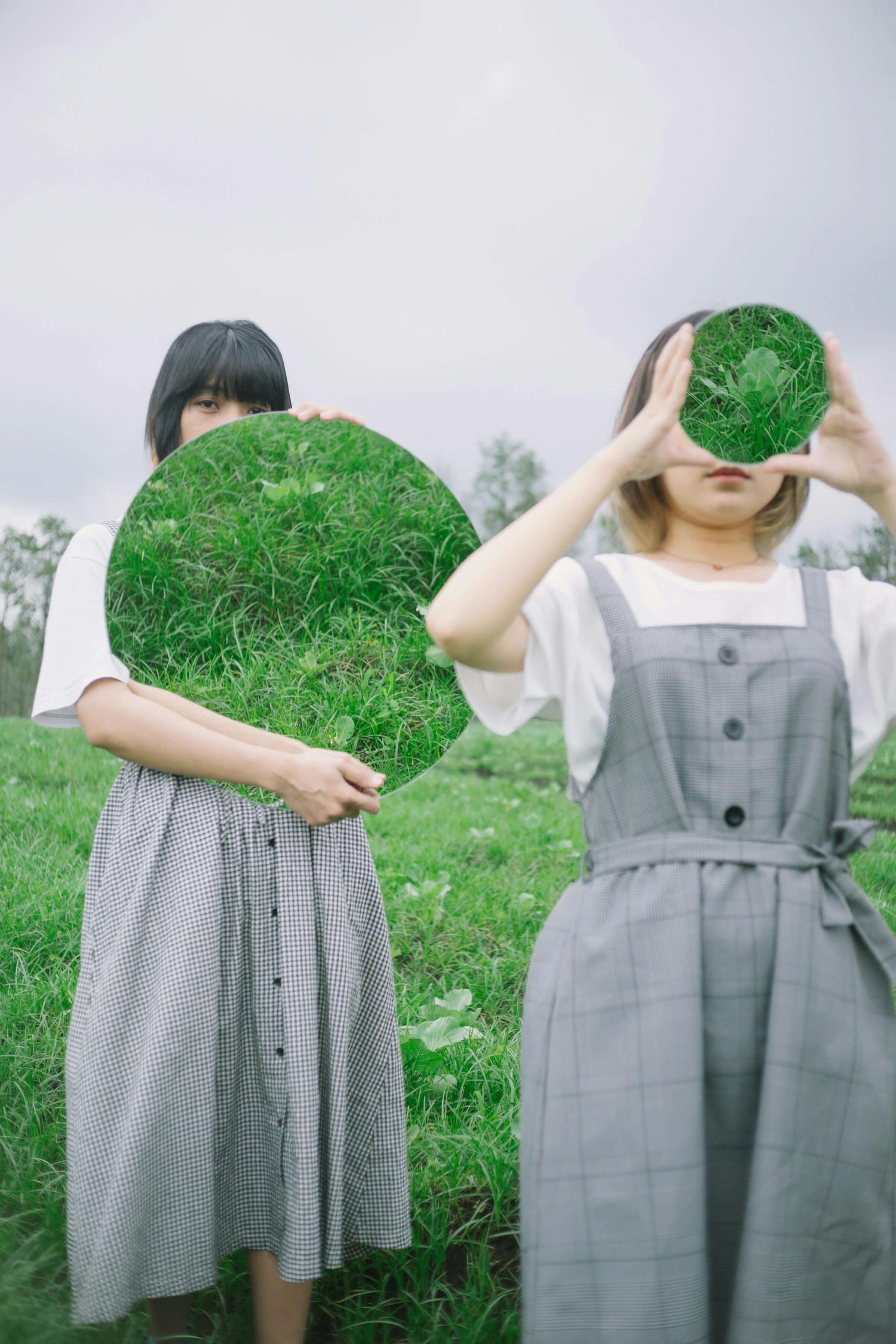 Two women standing in a field, surrounded by greenery, with a distinct green circle in the center.