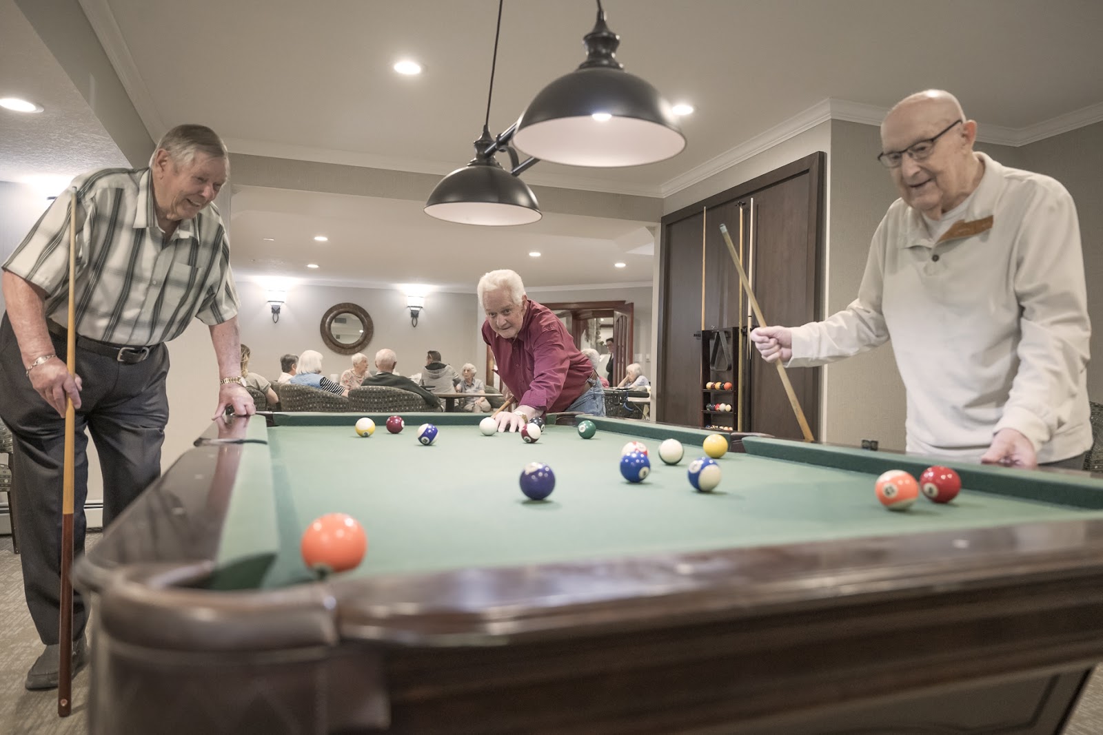 older seniors enjoying playing pool in a assisted living community 