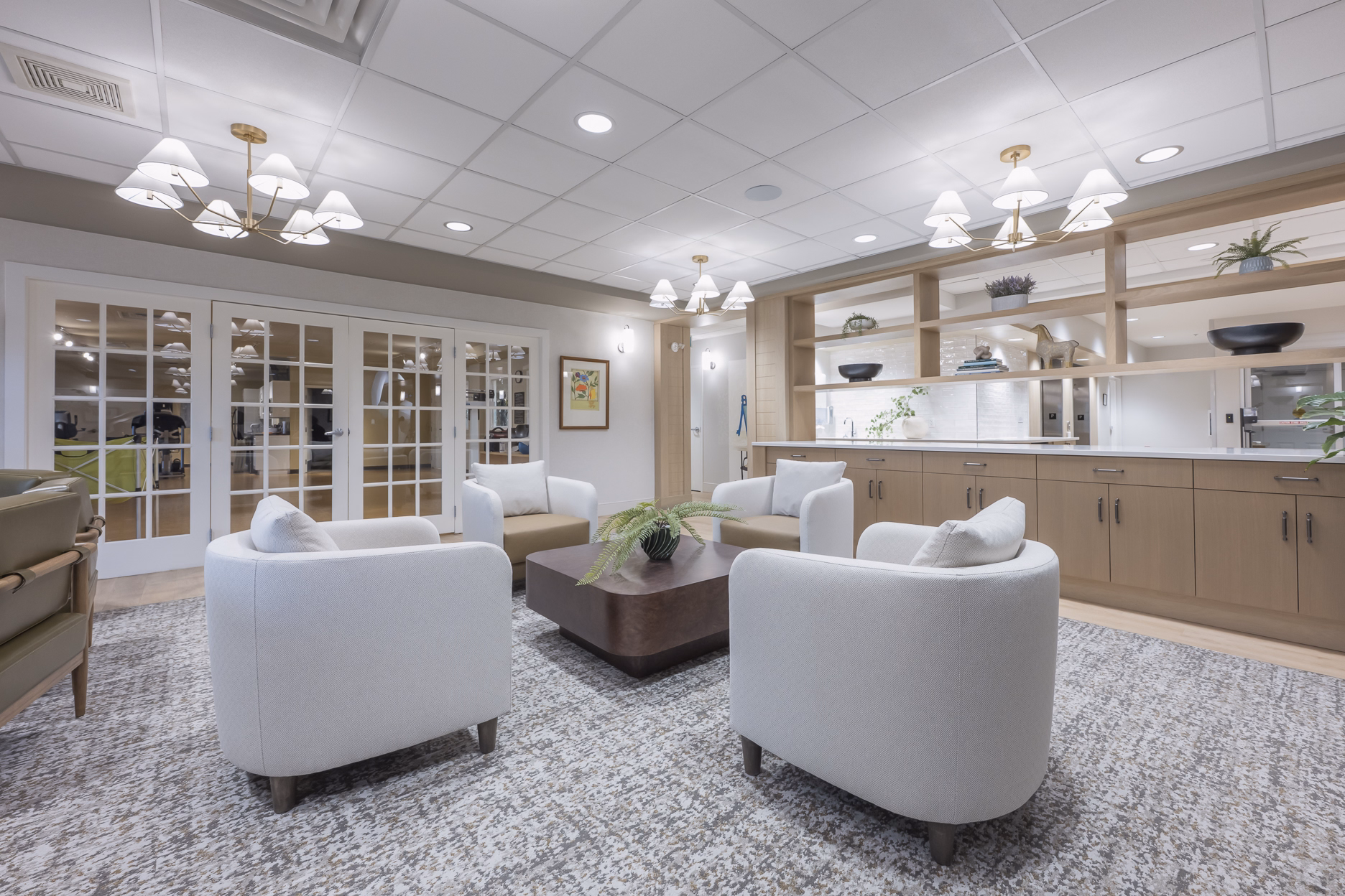 A bright lounge and conversation area with armchairs at United Active Living's Garrison Green community in Calgary