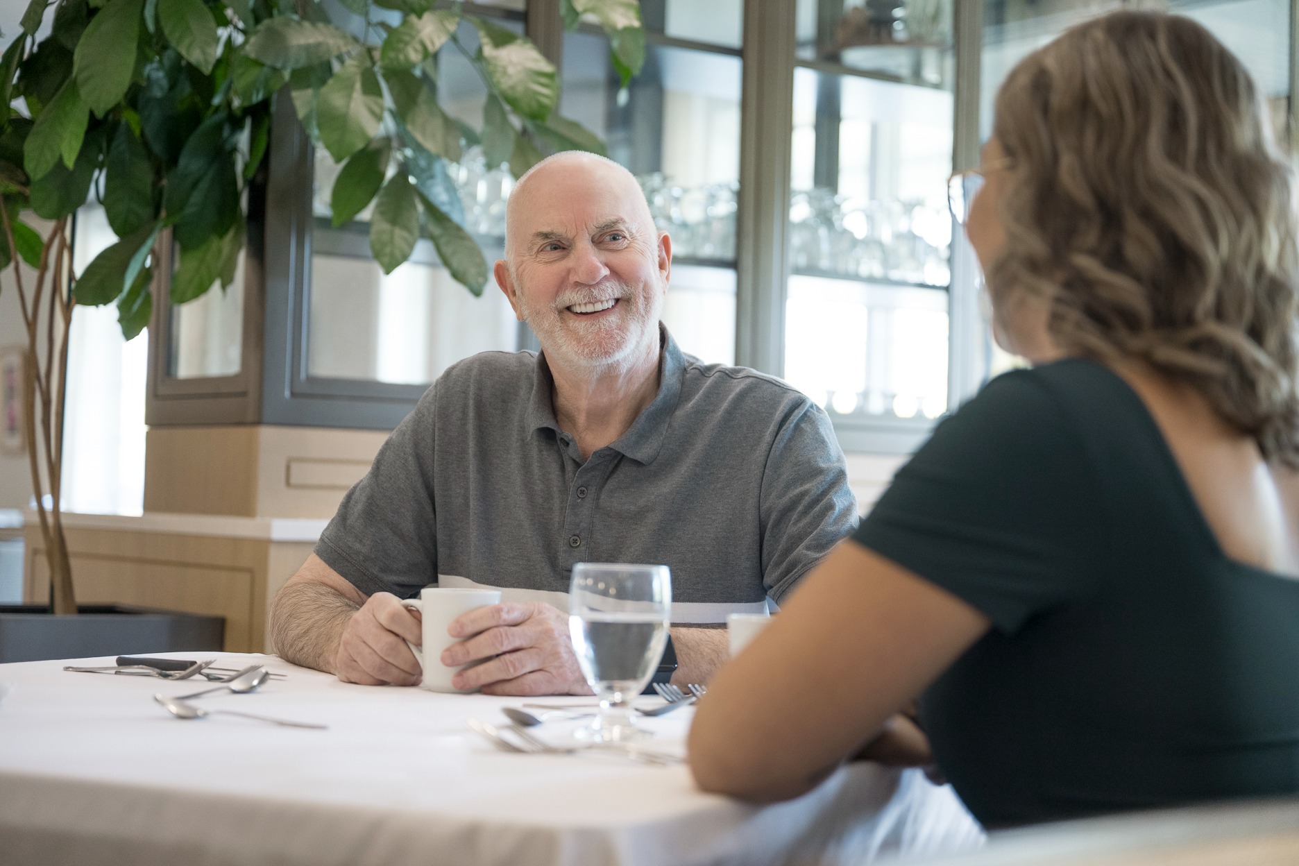senior man smiling sitting at table and talking with woman in retirement community
