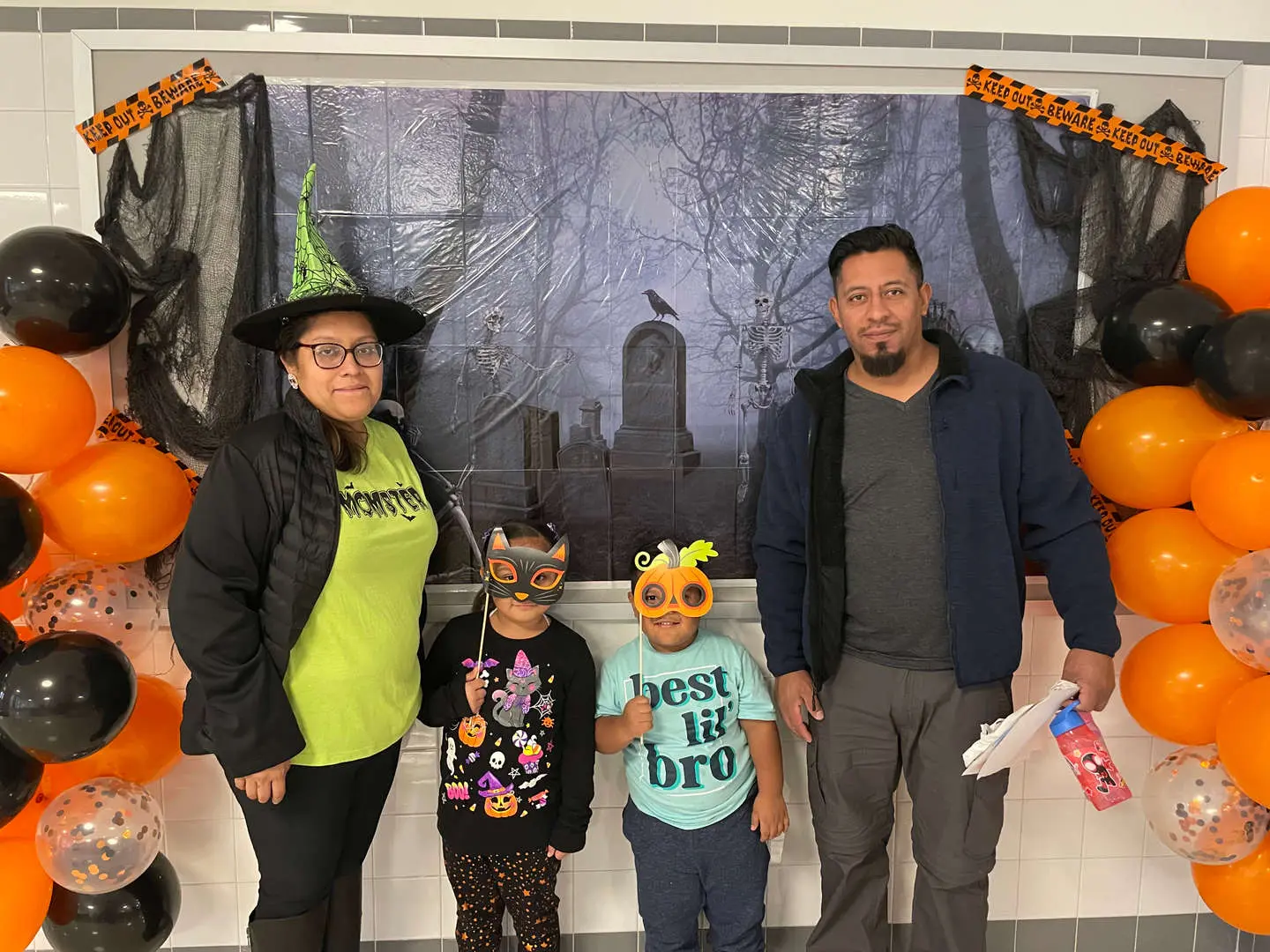 Family posing at school Halloween photo booth with costumes