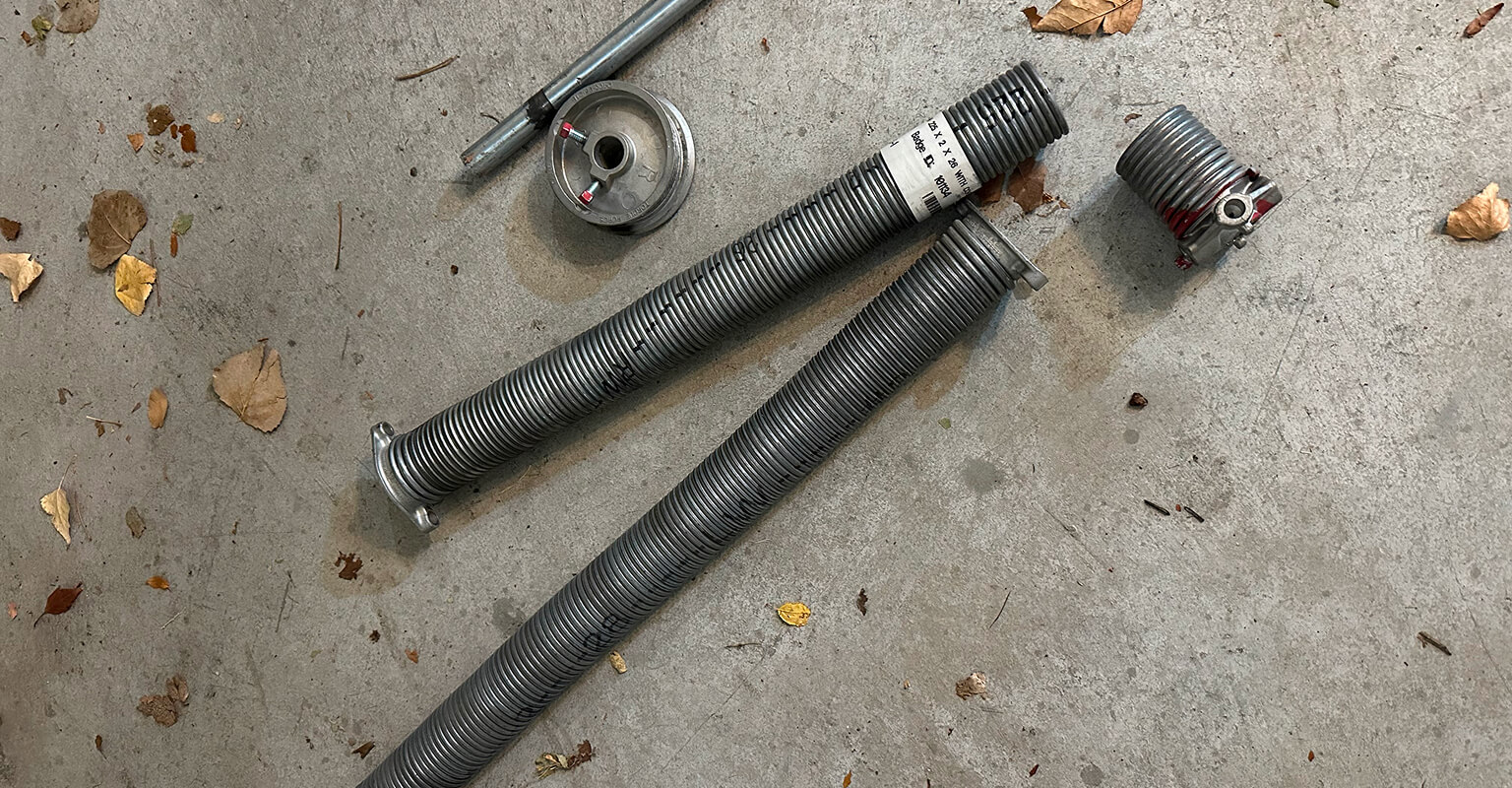 Broken garage door springs on the ground during a repair in Spanish Fork Utah, showing common spring failure homeowners experience.