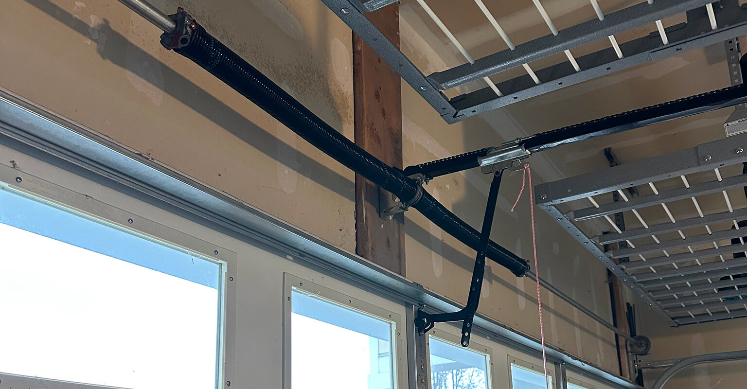 Technician adjusting a misaligned garage door track and hardware in Spanish Fork Utah to restore smooth door movement.