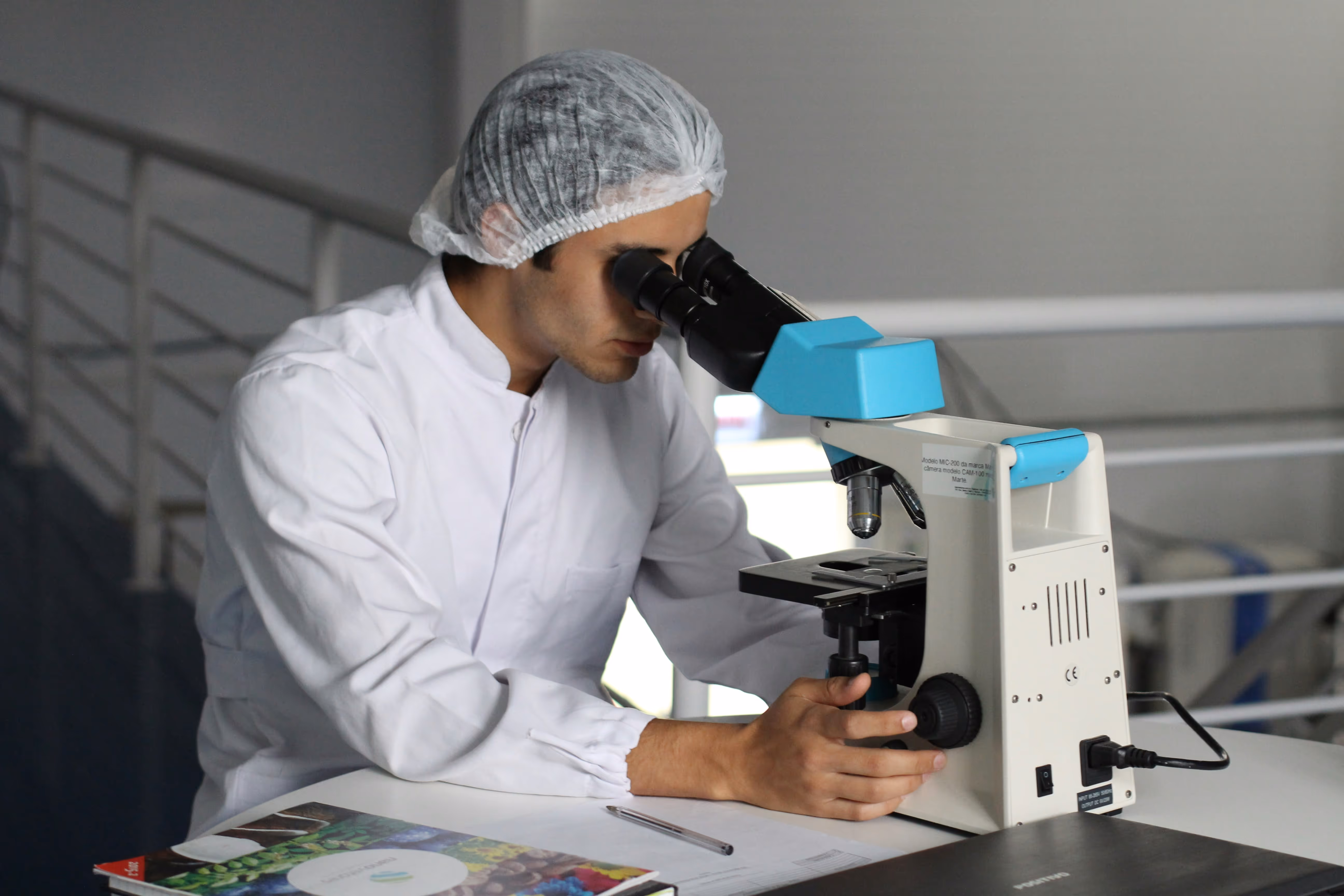 Scientist in lab coat using a microscope for medical or pharmaceutical research inside a laboratory