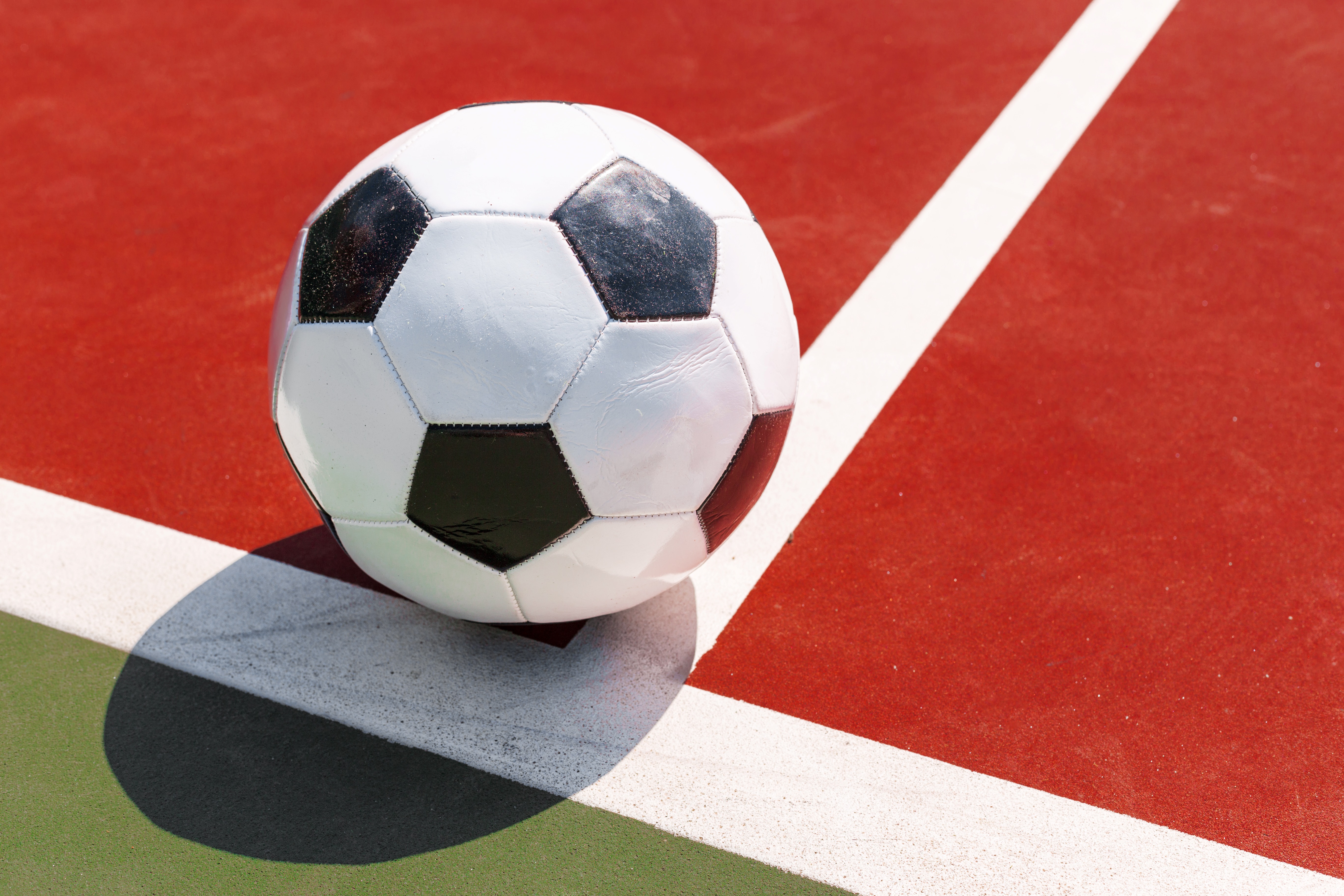 Fußball auf einem roten Spielfeld.