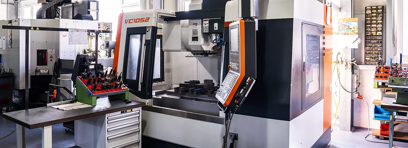 Industrial CNC machining center with control panel and tool holders in a workshop.