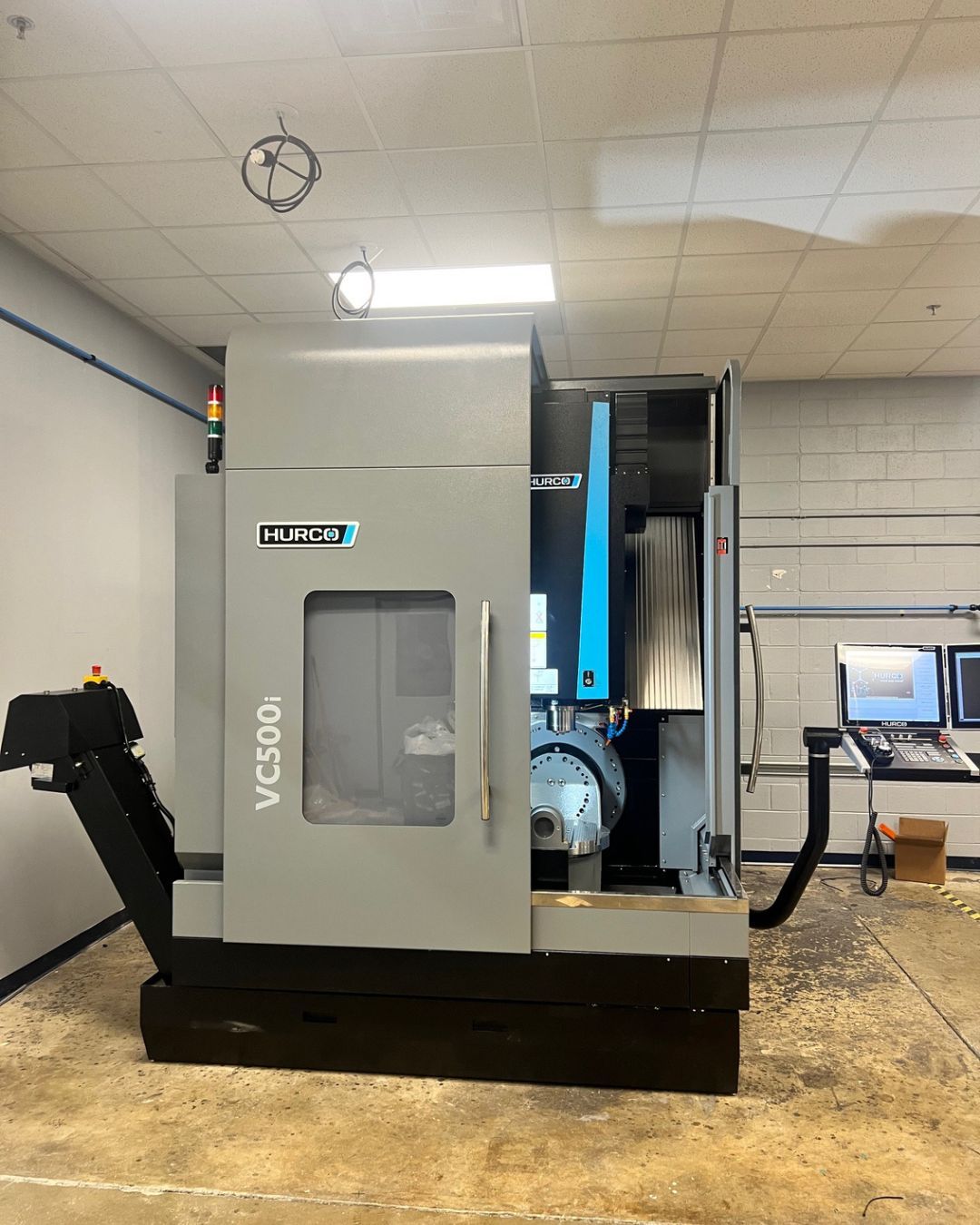 Hurco VC500i CNC machine in a workshop with control panels and concrete floor.