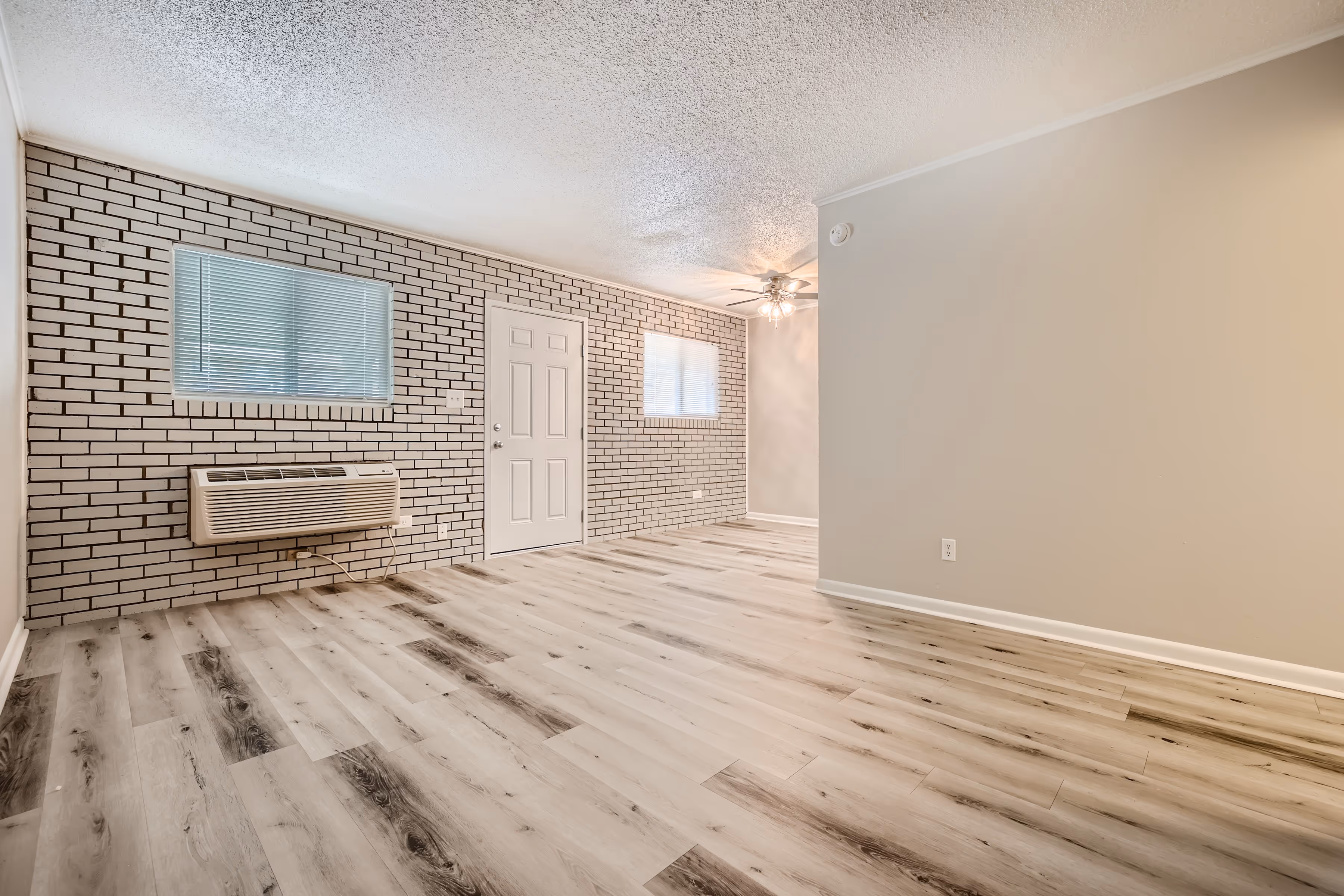 Living room and dining room with exposed white brick wall