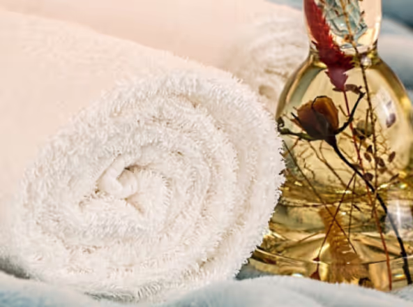 Massageöl und Handtücher liegen auf einem Massagetisch.