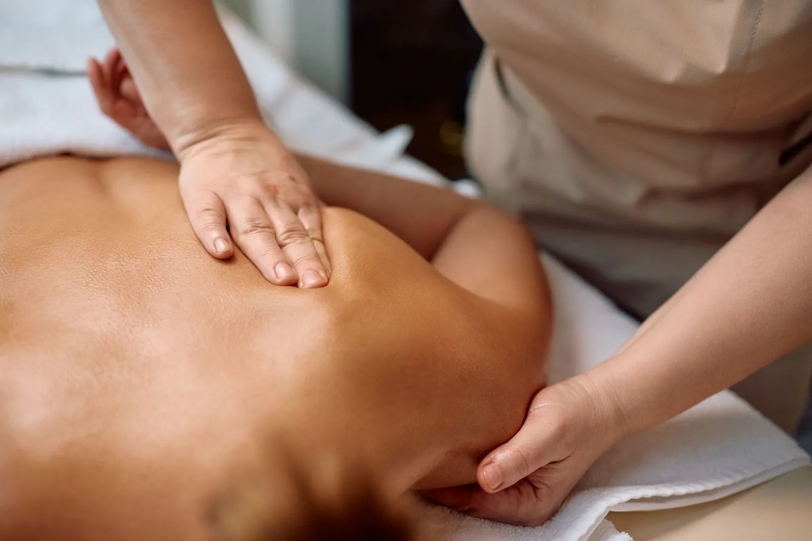 Eine Frau wird von einem professionellen Masseur an den Schultern massiert.