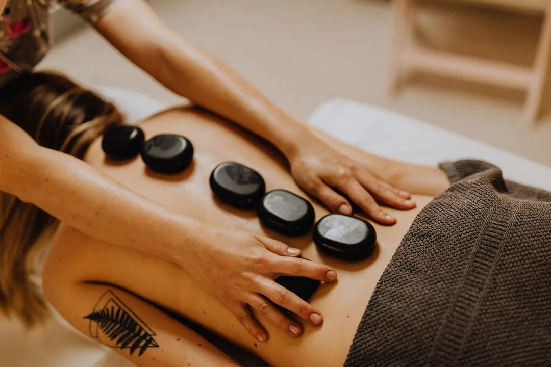 Eine Frau liegt auf einer Massageliege und bekommt eine Hot-Stone-Massage.