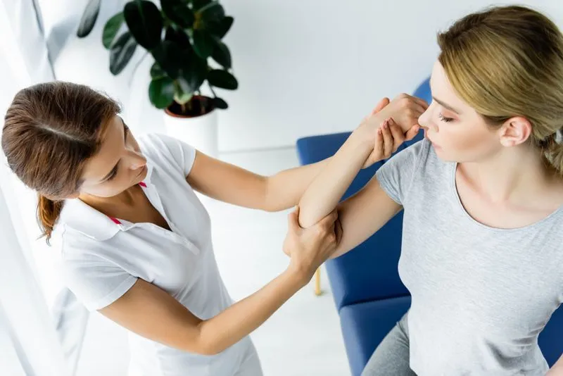 Eine Physiotherapeutin behandelt den rechten Arm einer Patientin mit manueller Therapie.