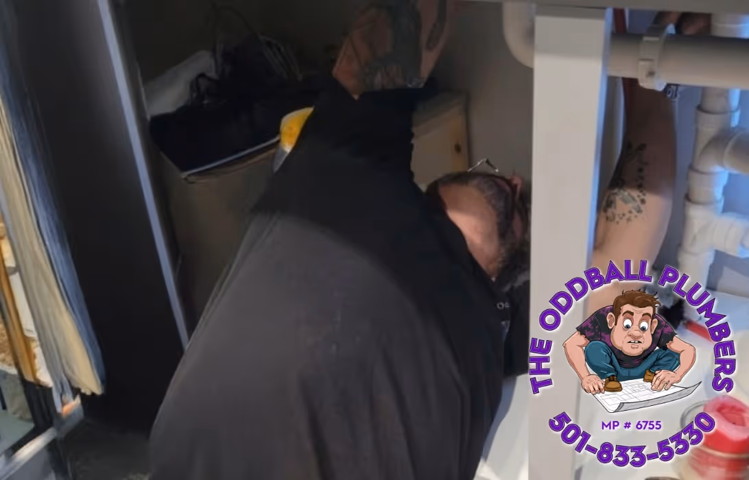 A Plumber under a sink repairing a leaky pipe.
