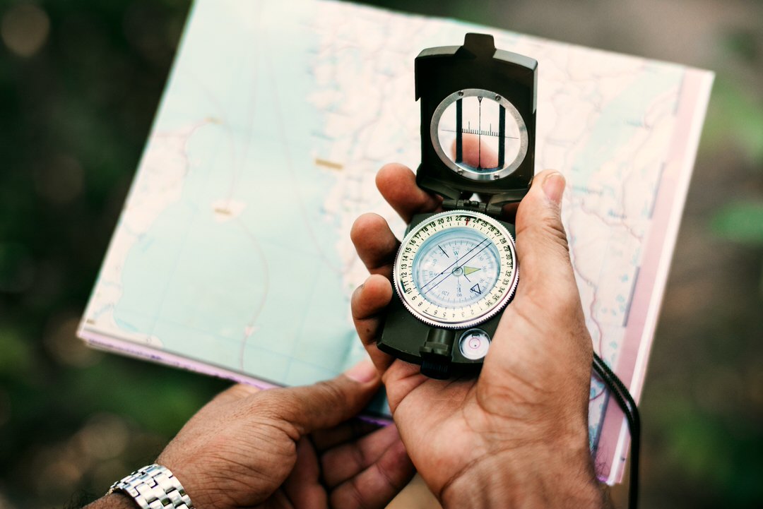Hand holding compass and map for navigation during outdoor exploration