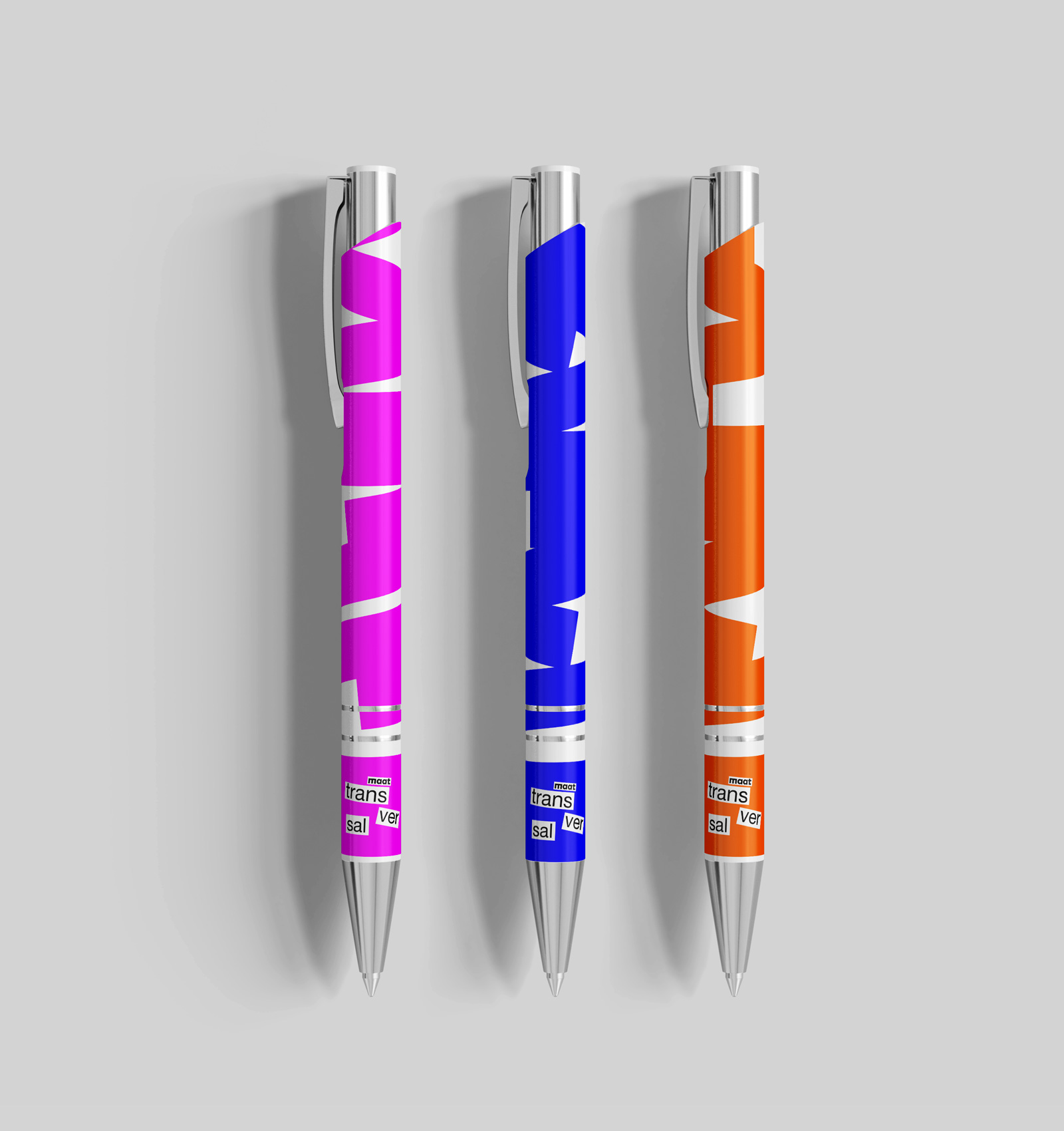 Three ballpoint pens with silver clips and tips, featuring colorful abstract designs in pink, blue, and orange, each labeled with 'maat transversal'.
