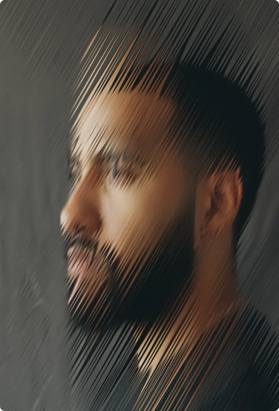 Side profile of a man with a beard behind textured glass creating streaked vertical distortion.