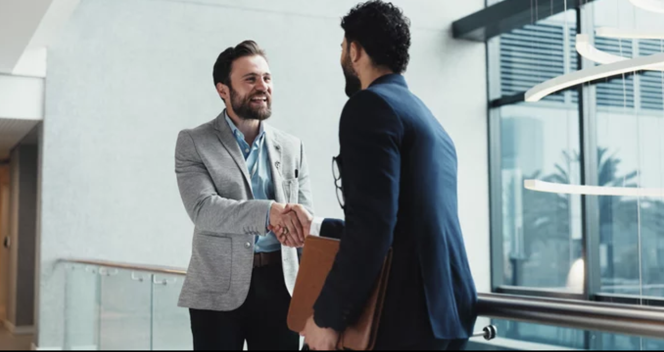 Business owner shaking hands with an advisor after a successful M&A deal.